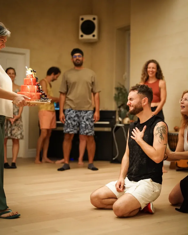 Hisham qui reçoit un gâteau de fête entouré d'amis danseurs et famille